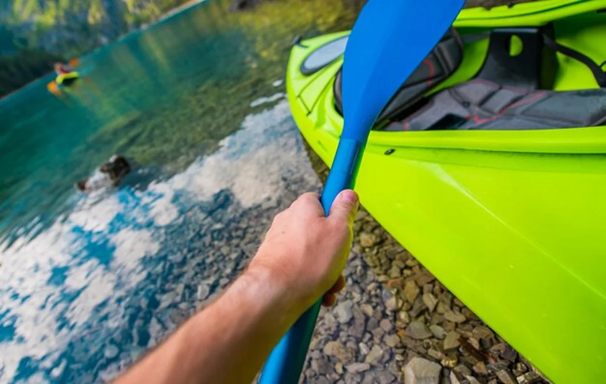 Osoba pływająca kajakiem na jeziorze w górach w słoneczny dzień